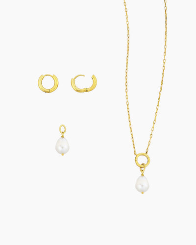 Gold huggie hoops with detachable freshwater pearl charm shown with a gold charm holder necklace