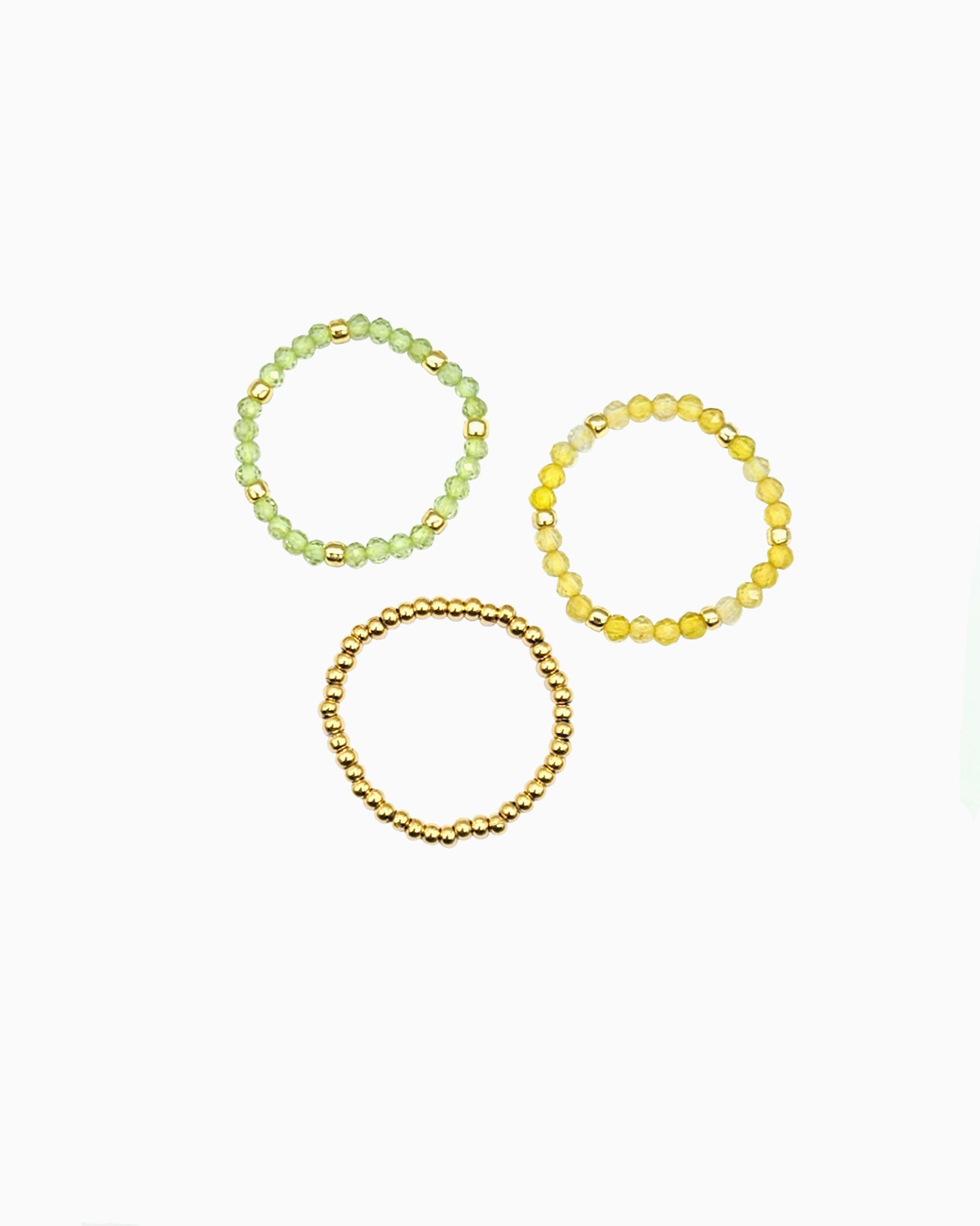 set of three stretch beaded rings in faceted peridot, yellow opal, and gold beads
