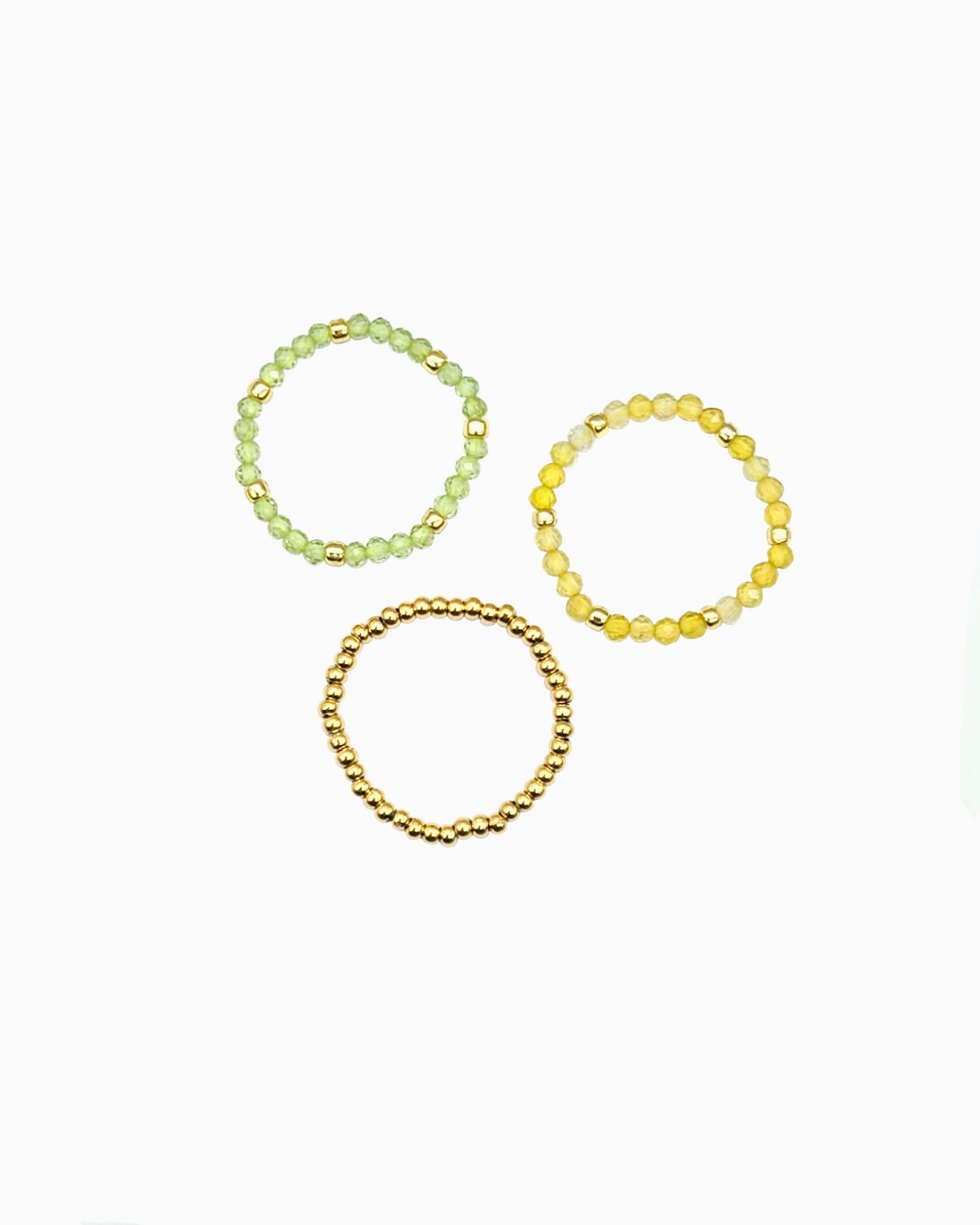 set of three stretch beaded rings in faceted peridot, yellow opal, and gold beads