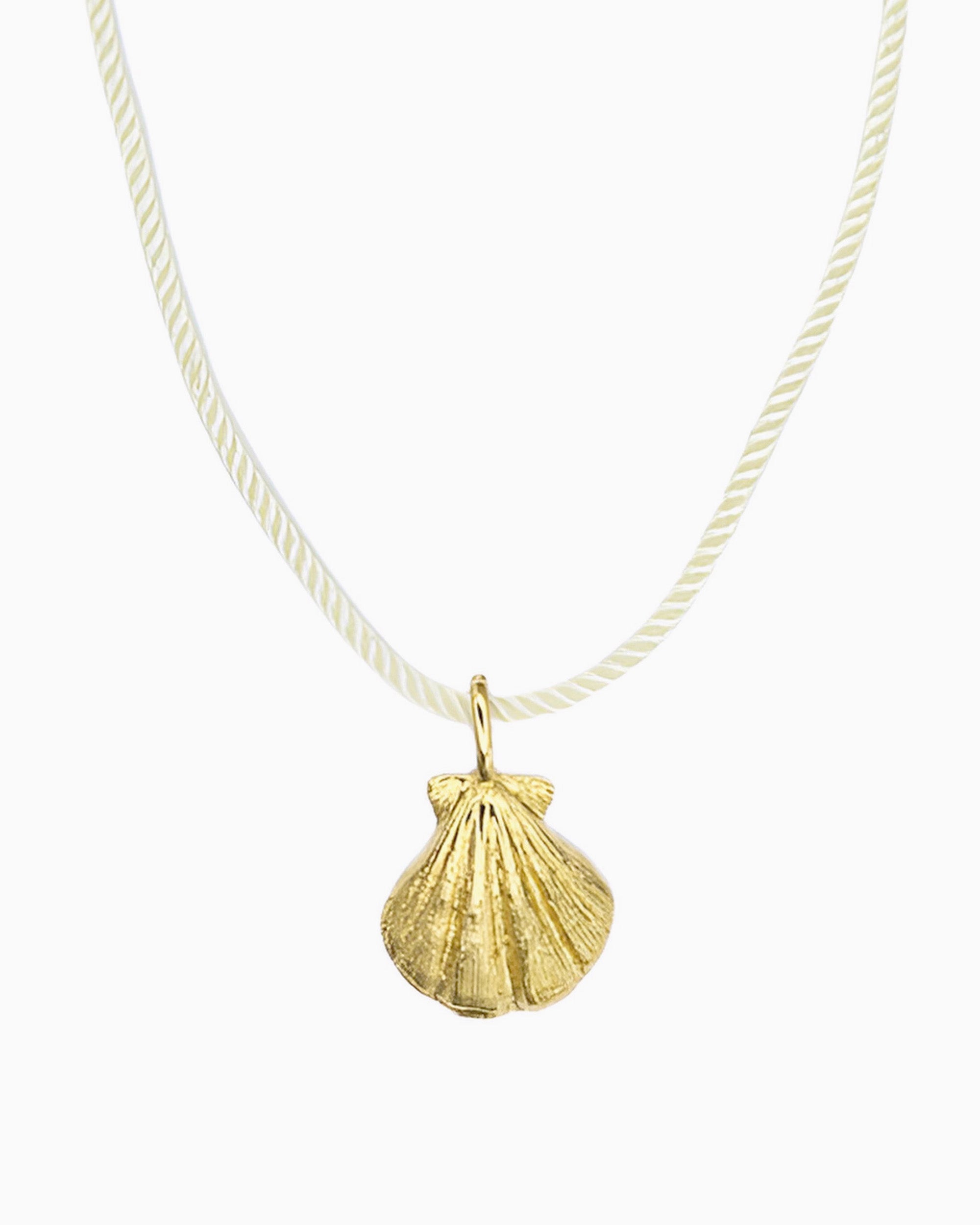 Ivory cord necklace featuring a detailed seashell clip-on charm inspired by a shell found along the shore.
